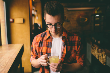 Young student is sitting in the restaurant and taste a warm drink. man drinking  tea at the cafe