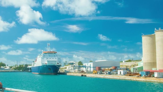 Cargo Ship in Tropical Water Docked at the Royal Naval Dockyard in Bermuda on a Sunny Day with White Clouds in a Blue Sky. All Recognizable Features Pertaining to the Vessel Hidden
