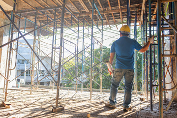 Construction manager with blueprints standing in front of construction site.