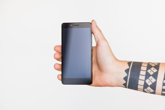 Male Hand With A Tattoo Holding Smartphone On White Background. Branding Mock-Up.