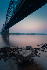 Fototapeta na wymiar River bank at Kiev, under the Darnitskiy bridge across Dnepr river against sunset sky. Ukraine