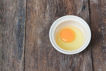 Raw egg in a bowl selective focus on wooden table