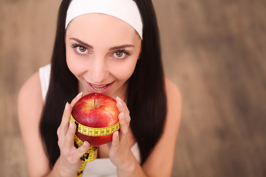 Young pretty woman is holding apple and measure tape. Healthy food concept.