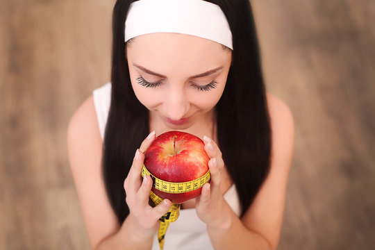 Young pretty woman is holding apple and measure tape. Healthy food concept.