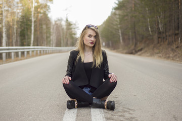 Beautiful young girl sitting in the middle of the road.