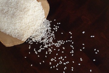 White rice in paper bag on wood background