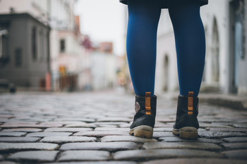 Female legs in trendy boots on cobblestone pavement