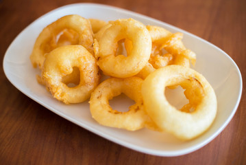 Fried onion rings on white dish. Fast food