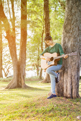 Young asian girl in forest with guitar, selective focus