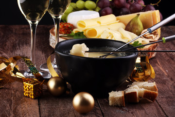 Gourmet Swiss fondue dinner on a winter evening with assorted cheeses on a board alongside a heated...