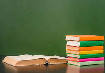 Books near empty green chalkboard. Space for text