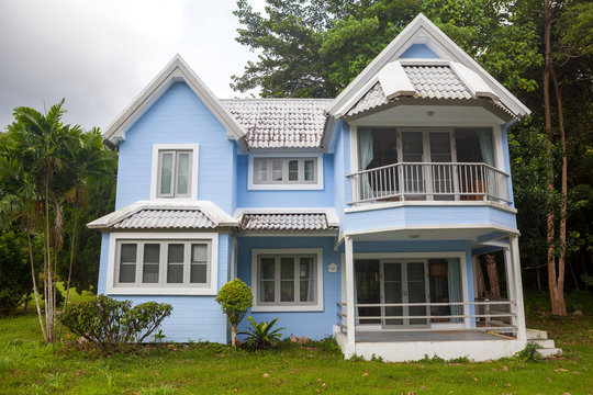 Beautiful Blue House Green Grass And Big Tree In Forest