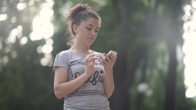 Beautiful curly girl run in the park adn use phone