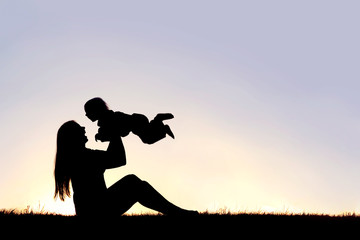 Silhouette of Happy Mother Playing Outside with Laughing Baby