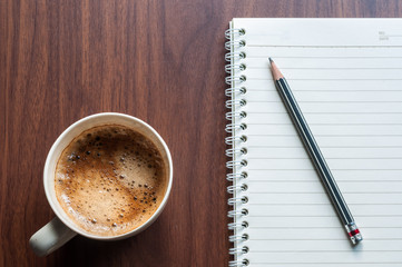 Coffee cup ceramic with notebook on wood table.