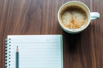 Obraz na płótnie Canvas Coffee cup ceramic with notebook on wood table.