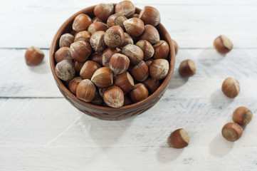 Hazelnuts in shell in brown clay bowl, top view