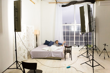 Backstage photo of bedroom during photo session. Many photo equipment for making photos of modern bedroom. Backstage concept.