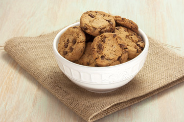 Bowl of chocolate chips cookies on burlap with copyspace