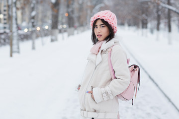 Beautiful young woman wearing merino wool pastel colors hat morning outdoors. Skin Care, Lip care, care of the eyelashes in the winter season. Beauty young woman Having Fun in Winter Park.

