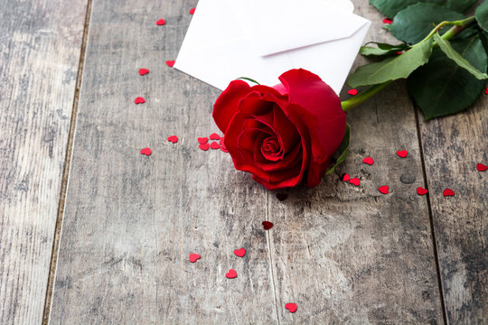Rose, envelope and hearts on wooden background
