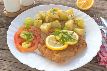 Wiener schnitzel with potatoes in plate on table