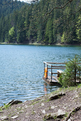 observation deck with lifebuoy on a mountain lake Synevir and coniferous trees