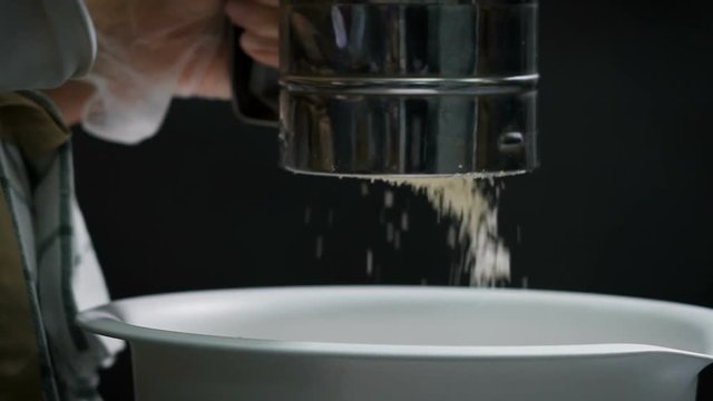 Professional chef with the help of a special device crushes the ingredients for cooking dough and sweets. The crumbs fall into the pot.
