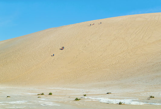 Tourists on the slope of the Dune 7 in Sossusvlei plato of Namib Naukluft National Park - Namibia, South Africa