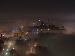Bergamo - Old city (Cittˆ Alta). One of the beautiful city in Italy. Lombardia. The fog rises from the plains and wrap all the old city by creating lighting effects.