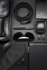 Man accessories in business style, silk tie, gadgets, briefcase, clothes and other luxury businessman attributes on leather black background, fashion industry, top view  - 131821199