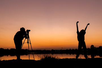 Silhouette man photographer and girl  jumping on sunset