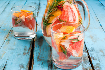 Refreshing summer detox cocktail of grapefruit and rosemary, on wooden rustic table, copy space 