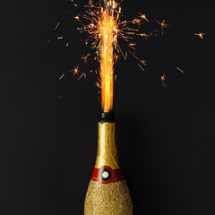 Golden champagne party bottle with firework sparklers on dark ba © Zamurovic Brothers
