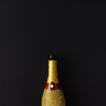 Golden champagne party bottle on dark background. Flat lay. Cele
