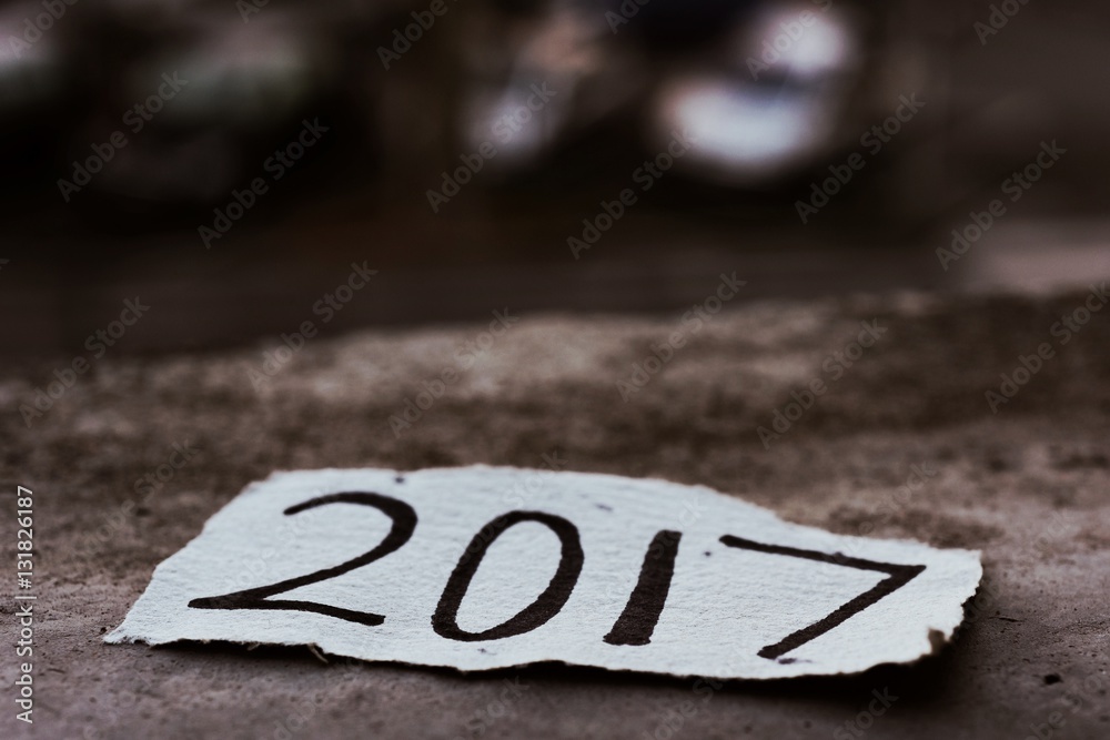 Poster closeup of a piece of paper with the number 2017, as the new year, written in it on the ground