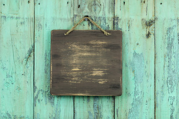 Blank wood sign hanging on rustic painted fence
