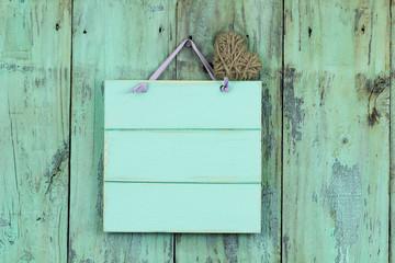 Blank mint green sign with heart hanging on rustic background