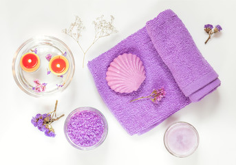 Spa products. Lavender bath salts, dry flowers, soap, cosmetic cream, light candles and towel. Violet purple concept. Flat lay on white background, top view.