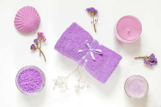 Spa products. Lavender bath salts, dry flowers, soap, cosmetic cream, candles and towel. Violet purple concept. Flat lay on white background, top view.