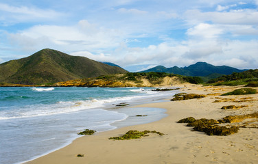 The shore of a beach with mountains in the background.