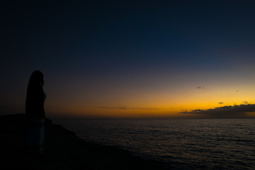 Naklejka na ściany i meble Woman watching the sunset in Tenerife, Spain