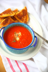 Bowl of tomato soup with fresh thyme and creme fraiche and a grilled cheese sandwich