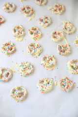 Homemade white chocolate-covered pretzels with colorful sprinkles and copy space