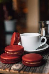 Macaroons with cup of coffee on wood plate, blur in background