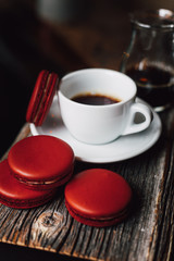 Macaroons with cup of coffee on wood plate, blur in background