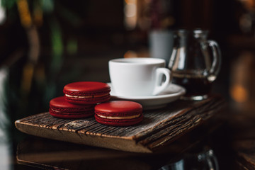 Macaroons with cup of coffee on wood plate, blur in background