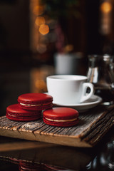 Macaroons with cup of coffee on wood plate, blur in background