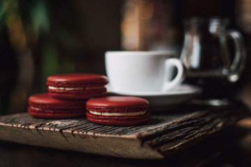 Obraz na płótnie Canvas Macaroons with cup of coffee on wood plate, blur in background