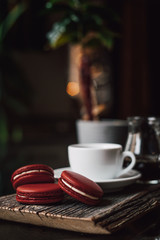 Macaroons with cup of coffee on wood plate, blur in background